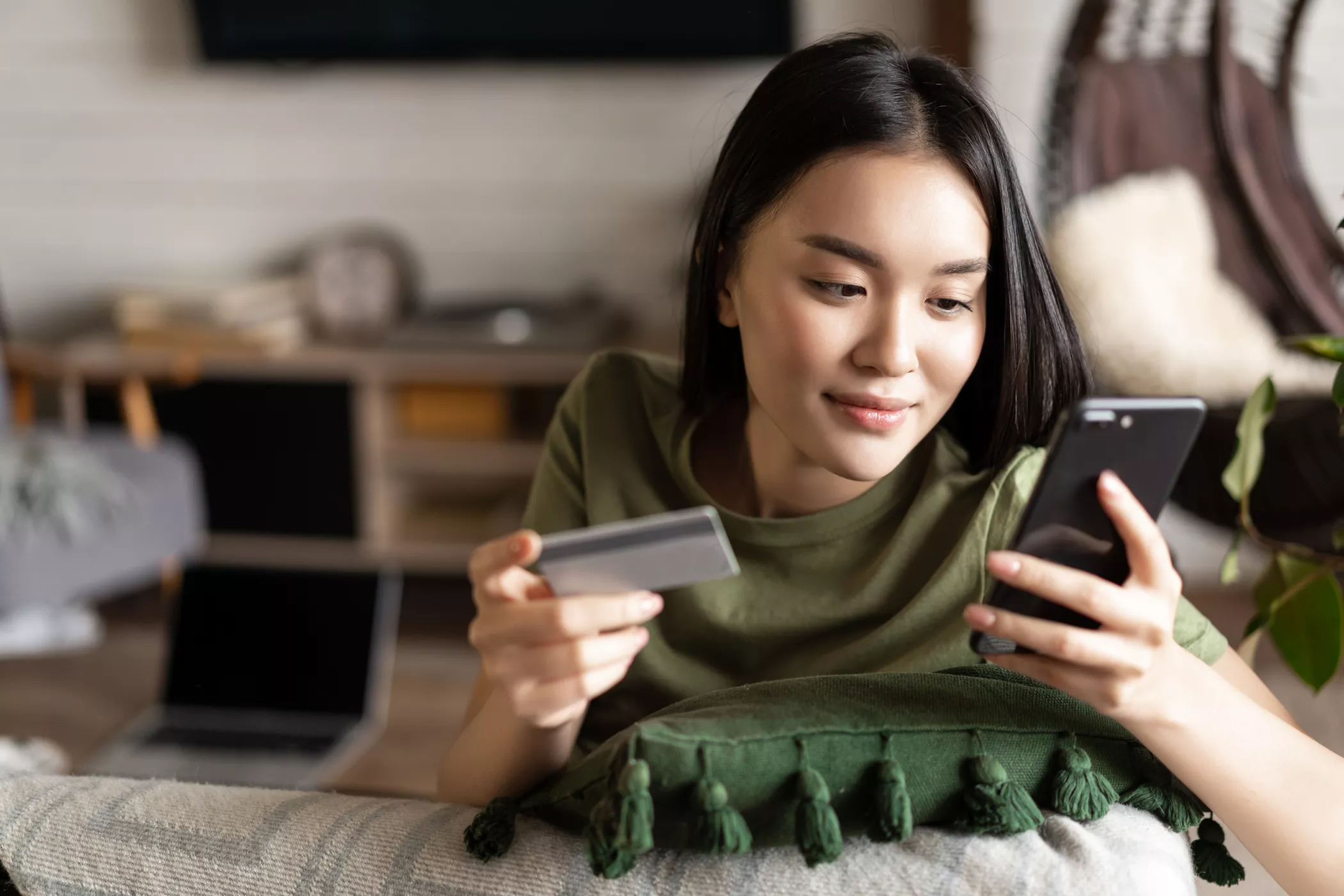 Young asian woman buying from online shop, using mobile phone and credit card, shopping from home.